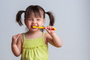 young girl with pigtails brushing her teeth