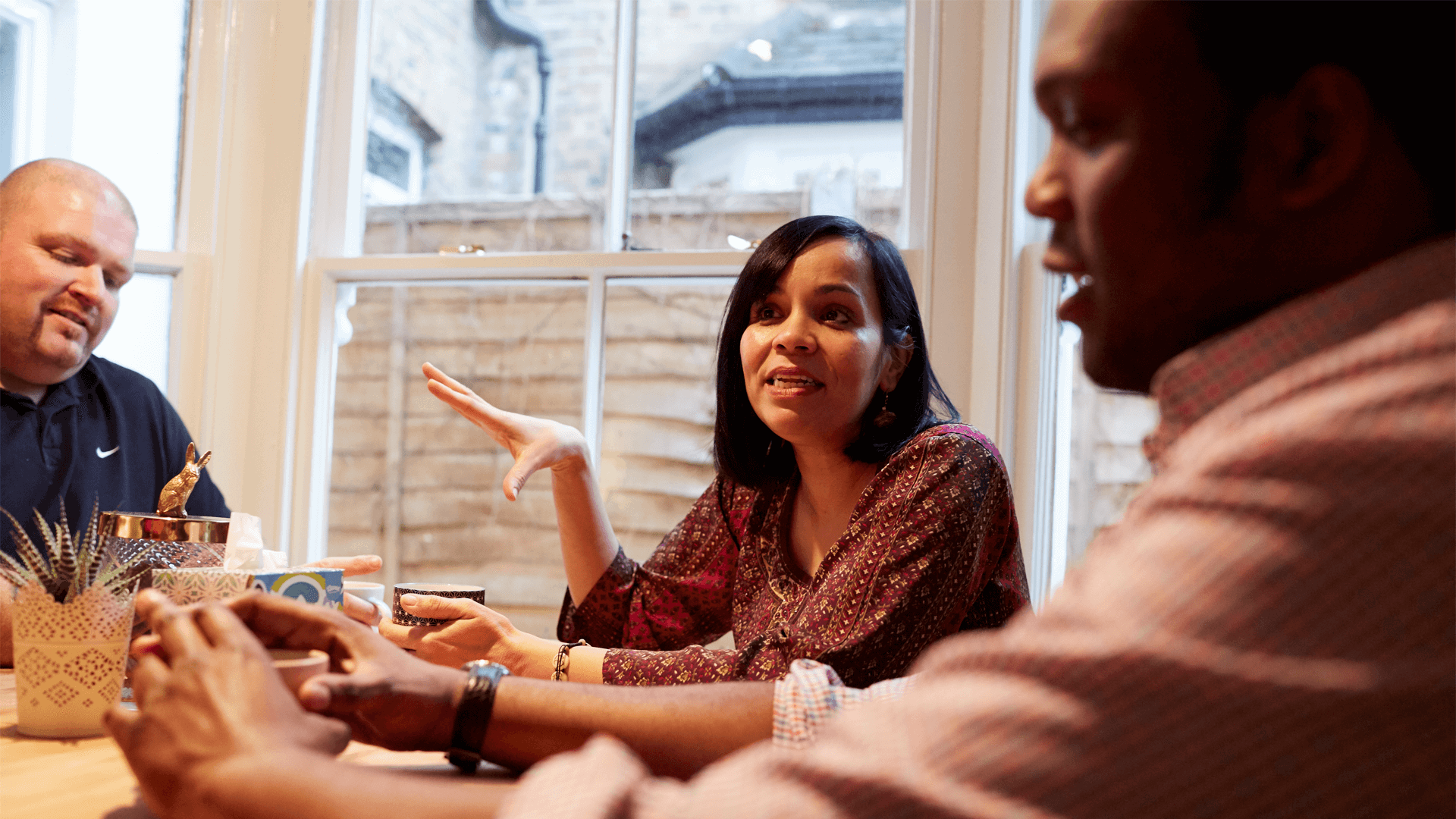 A group conversation at a table with two men and one woman