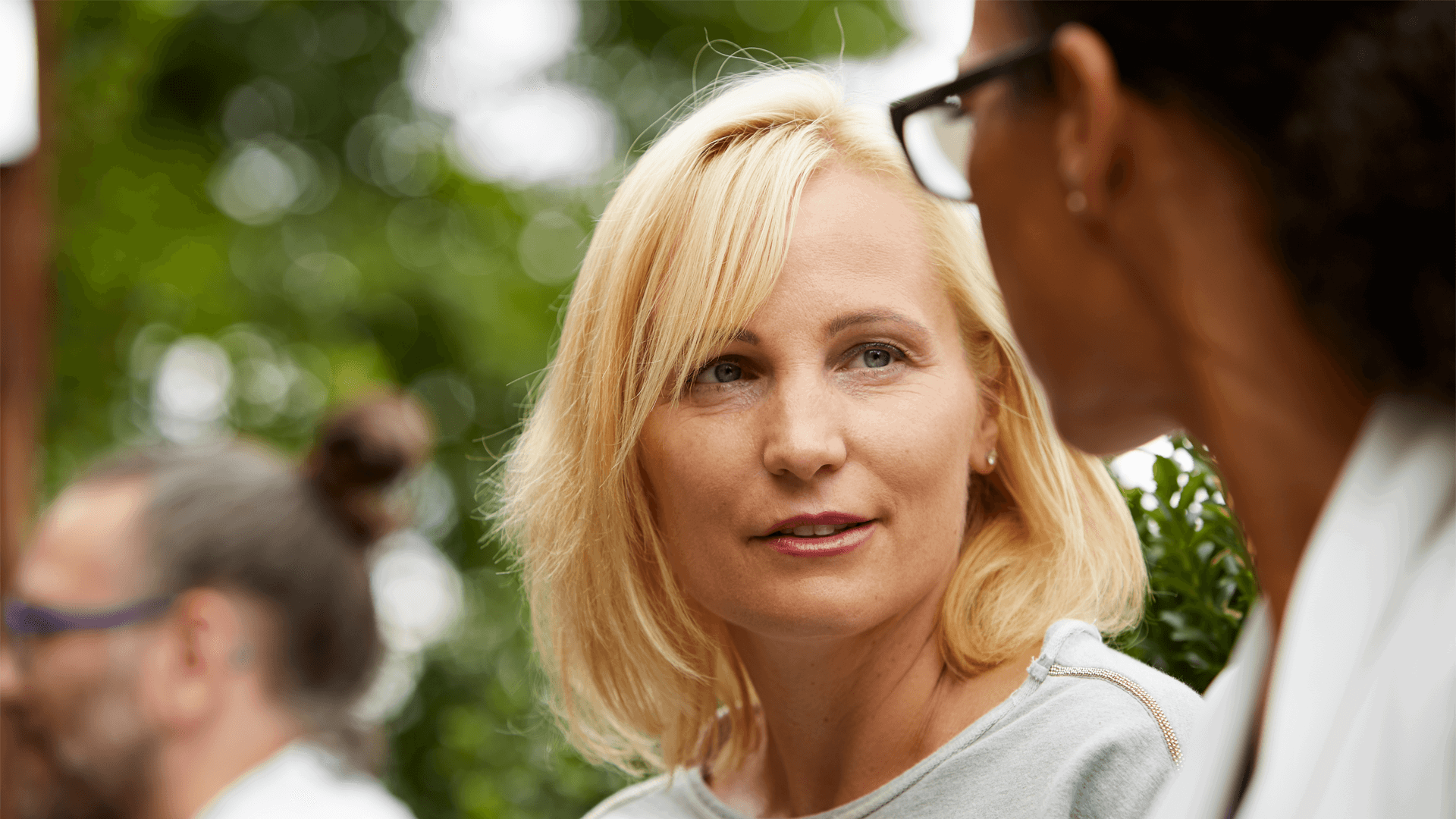 Two women outside in deep conversation with a tree behind them 