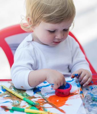 Baby dipping finger into color