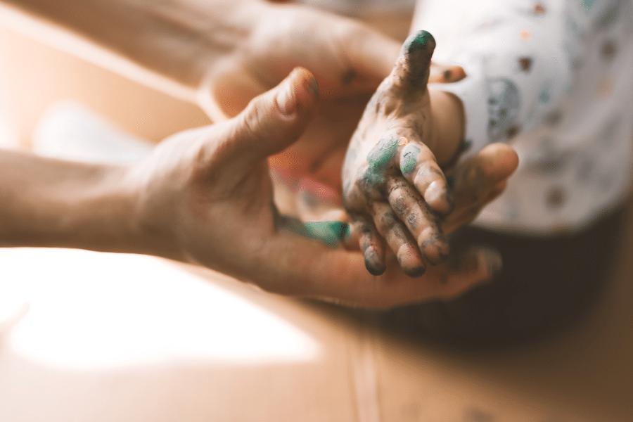 A close-up of an adult's hand reaching out to a child's small hand